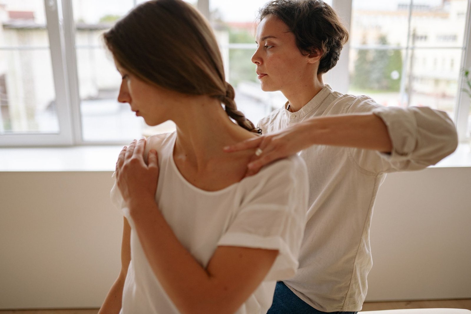 Une praticienne réalise un massage des épaules à une collaboratrice