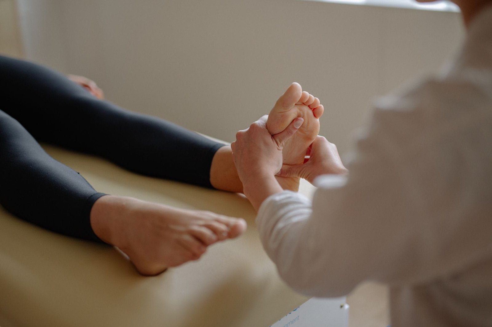 Séance de réflexologie plantaire : pressions manuelles sur le pied d’une personne allongée et habillée